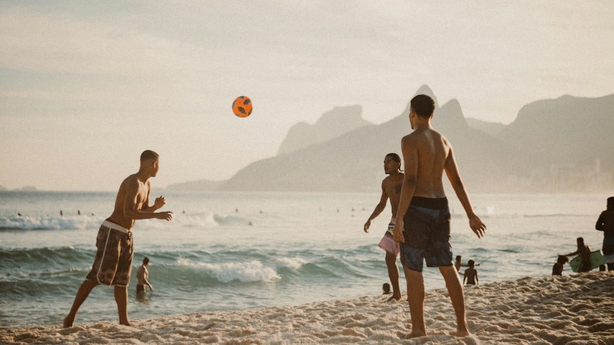 man in black shorts holding hands with woman in white tank top on beach during daytime
